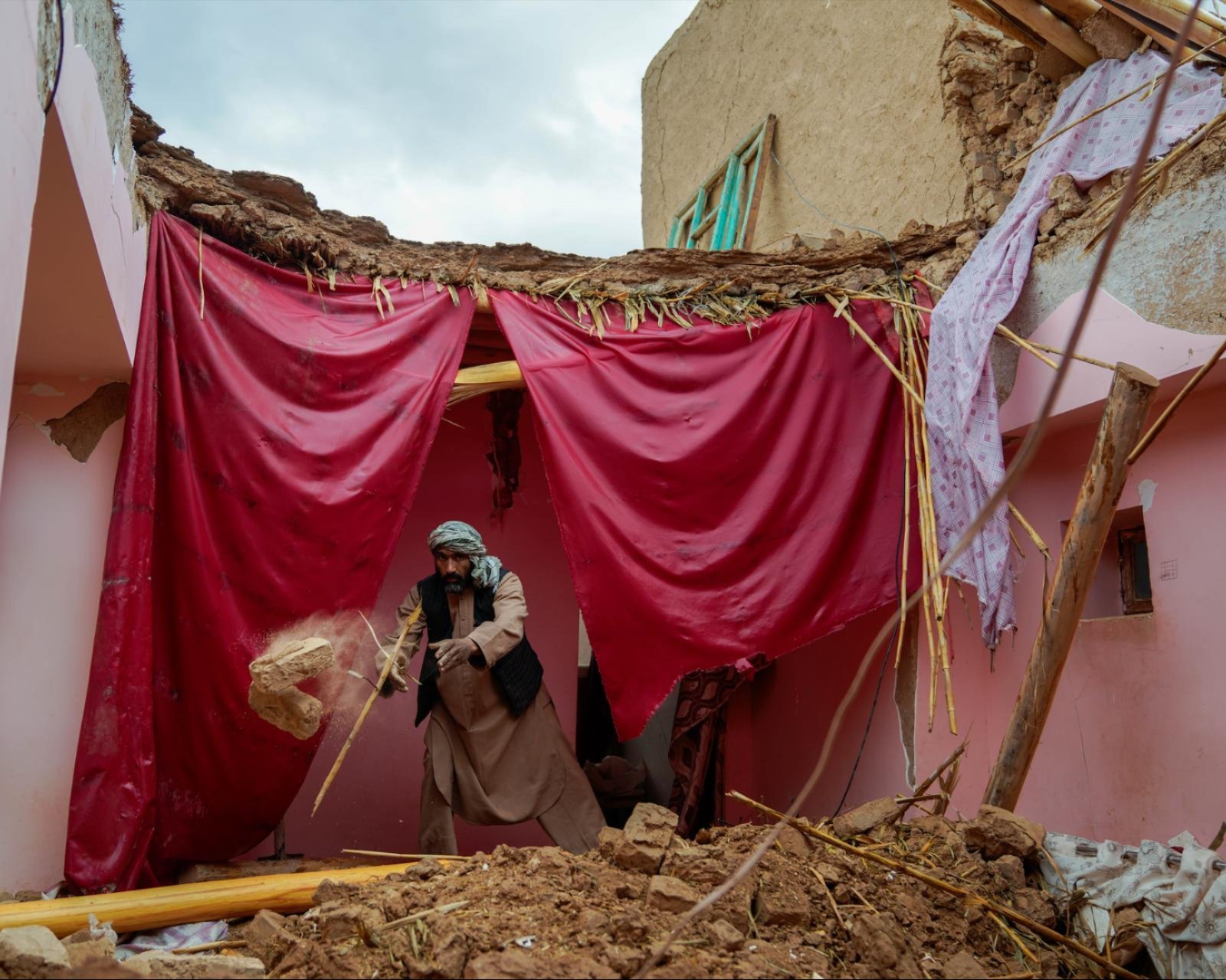 Zerst&ouml;rtes Haus in Afghanistan, Mann r&auml;umt Tr&uuml;mmer auf