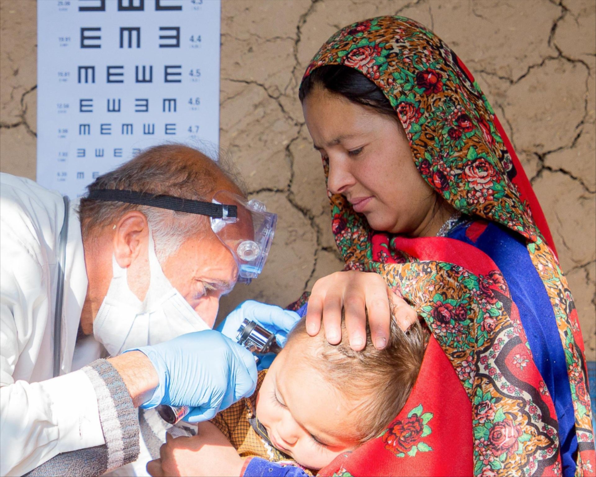 Arzt untersucht kleines Kind im Arm der Mutter