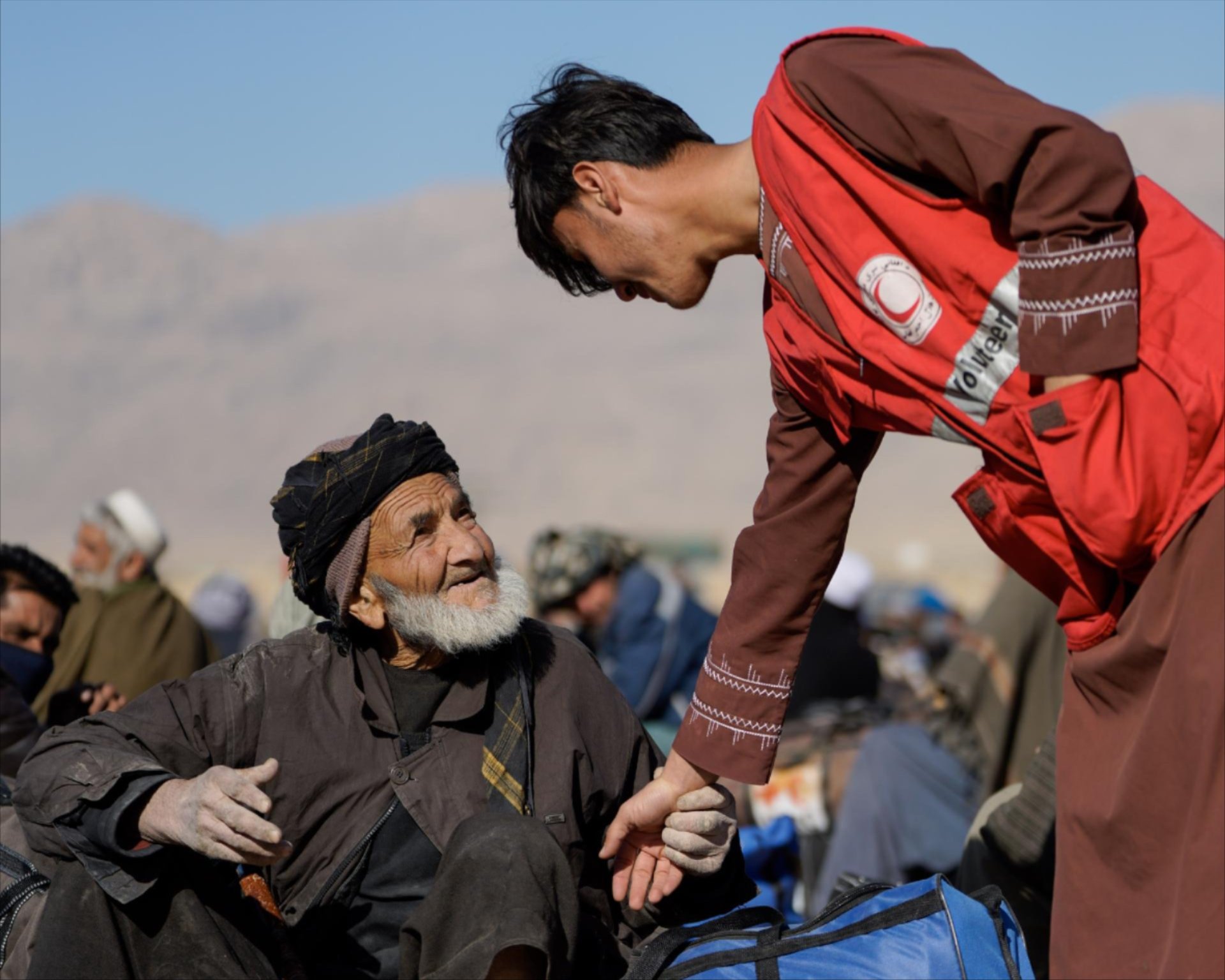 Junger Freiwilliger des Roten Halbmondes hilft Mann in Afghanistan